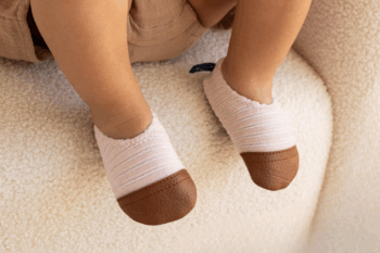 Les Petits Velours Rose pâle aux pieds d'un bébé