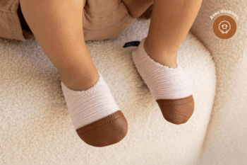 Les Petits Velours Rose pâle aux pieds d'un bébé