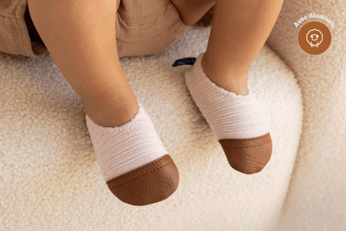 Les Petits Velours Rose pâle aux pieds d'un bébé