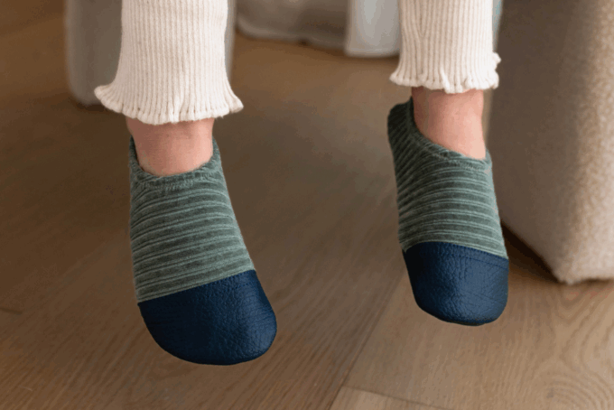 Les chaussons souples Les Petits Velours Gris vert aux pieds d'un enfant