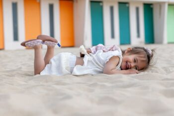 sac à dos Marguerites sur le dos d'une petite fille allongée dans le sable