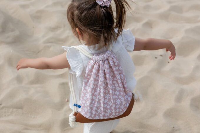 sac à dos Marguerites sur le dos d'une petite fille sur la plage