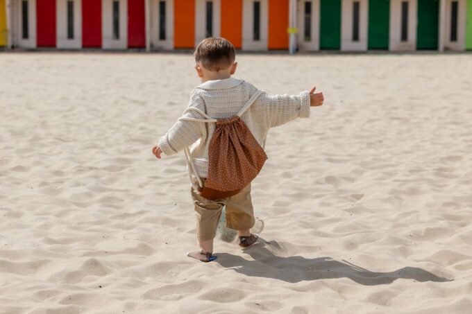 sac à dos Pois sur le dos d'un petit garçon à la plage