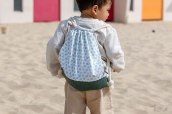 sac à dos Trèfles sur le dos d'un petit garçon sur le sable