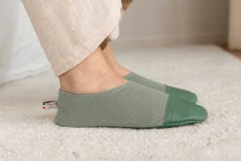 Les Petits Tricots Vert amande aux pieds d'une femme