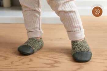 Les Petites Bouclettes Gris vert aux pieds d'un enfant