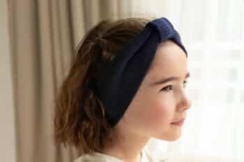 Les Petits Bandeaux Tricots Bleu profond dans les cheveux d'une petite fille